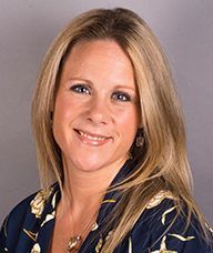 A woman with long blonde hair is smiling for the camera.