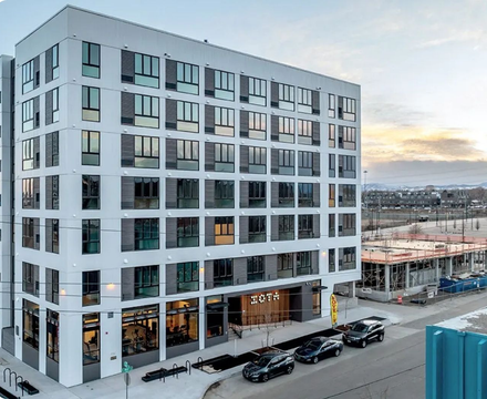White multi-story apartment building with large windows;