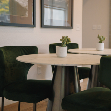 Two people working at a long table in a modern office, under large pendant lights.