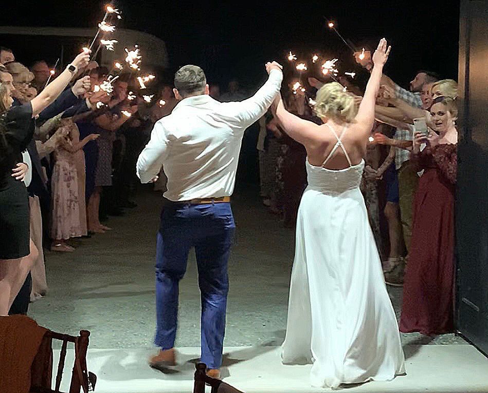 Newly wed couple leave venue through a sparkler sendoff.