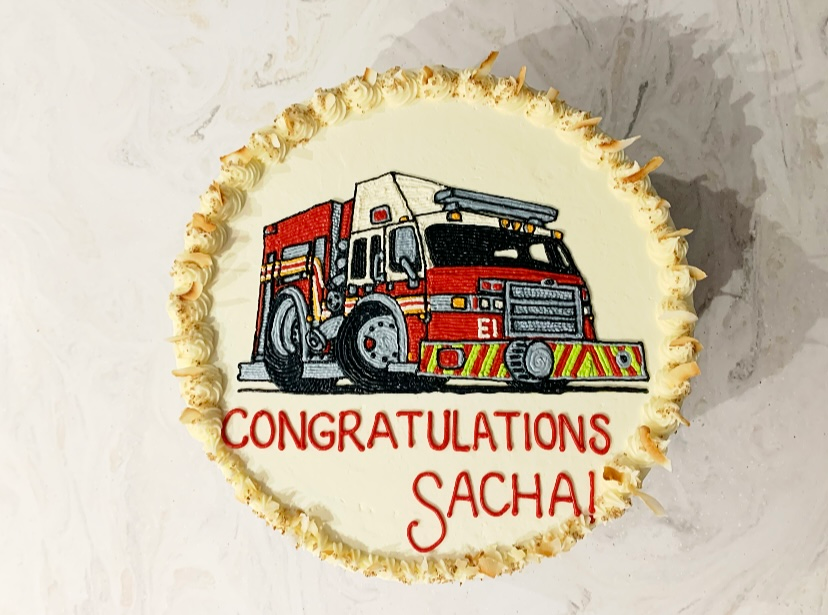 Mix It Up! cakes and cupcakes: White frosted cake with a firetruck drawn on the top saying Congratulations!