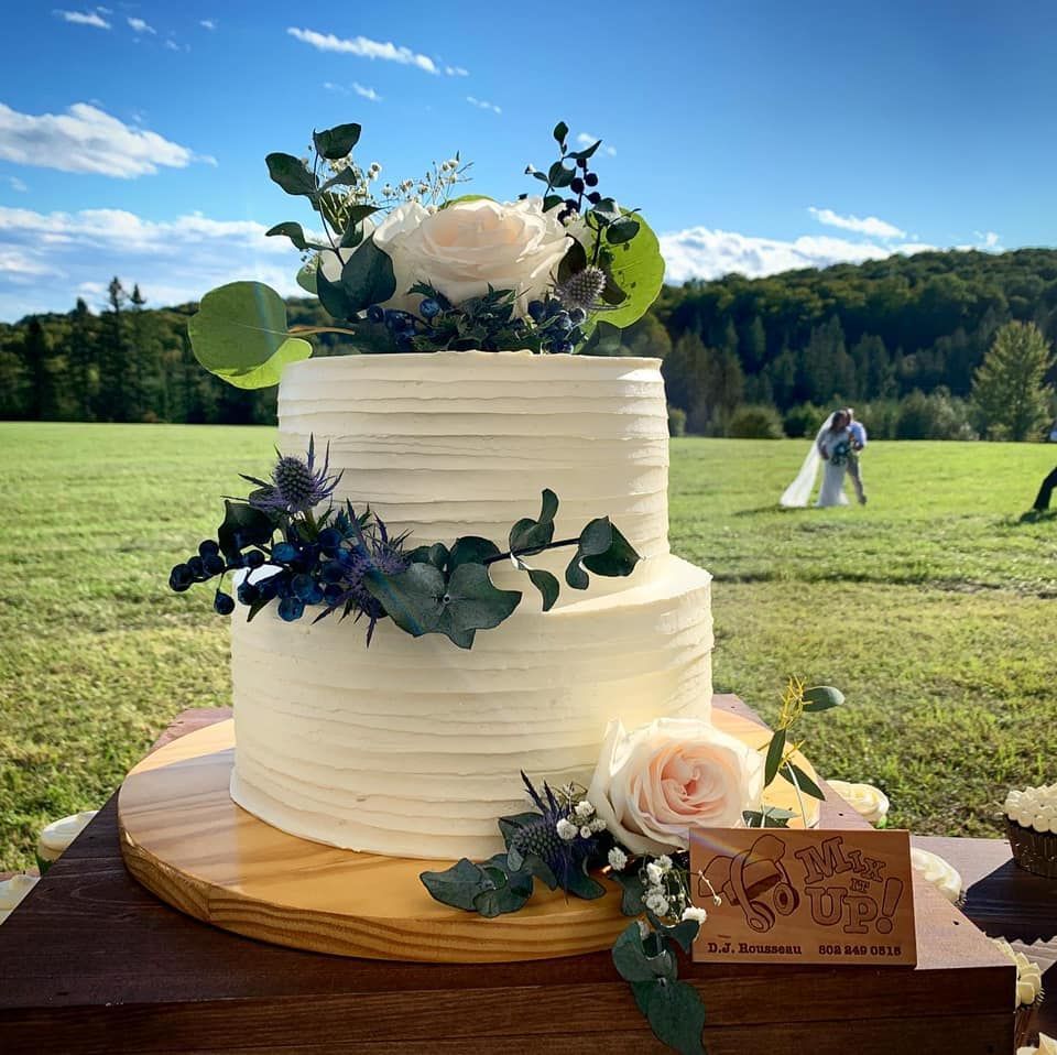 Mix It Up! custom wedding cakes 2 tier cake with white frosting with flowers and greenery on it