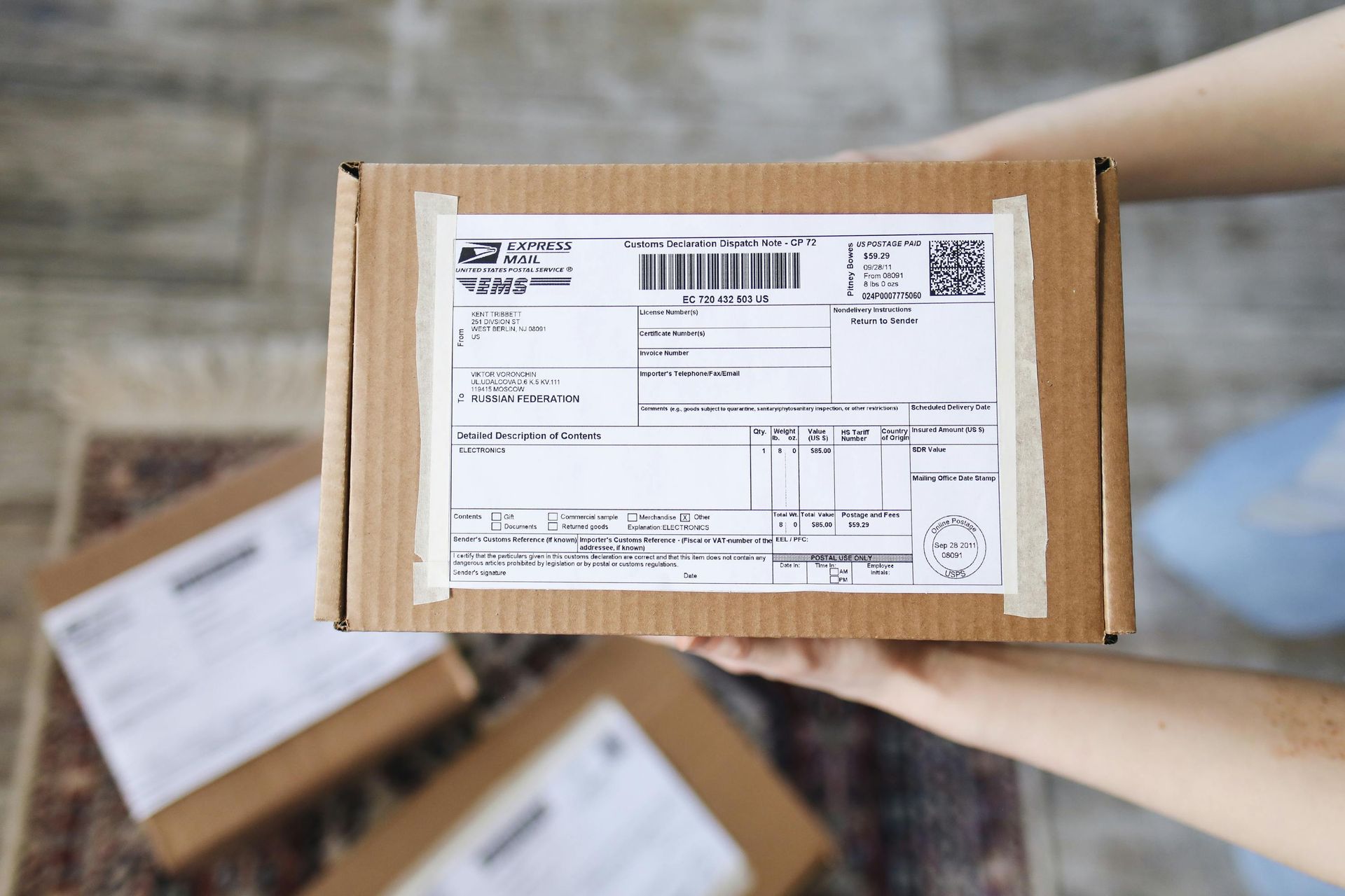 A person is holding a cardboard box with a shipping label on it.
