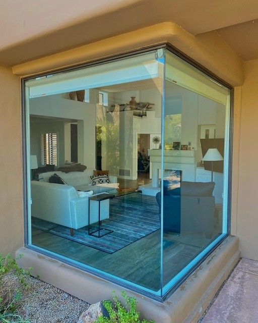 Corner window revealing a living room with white couch, blue rug, fireplace.