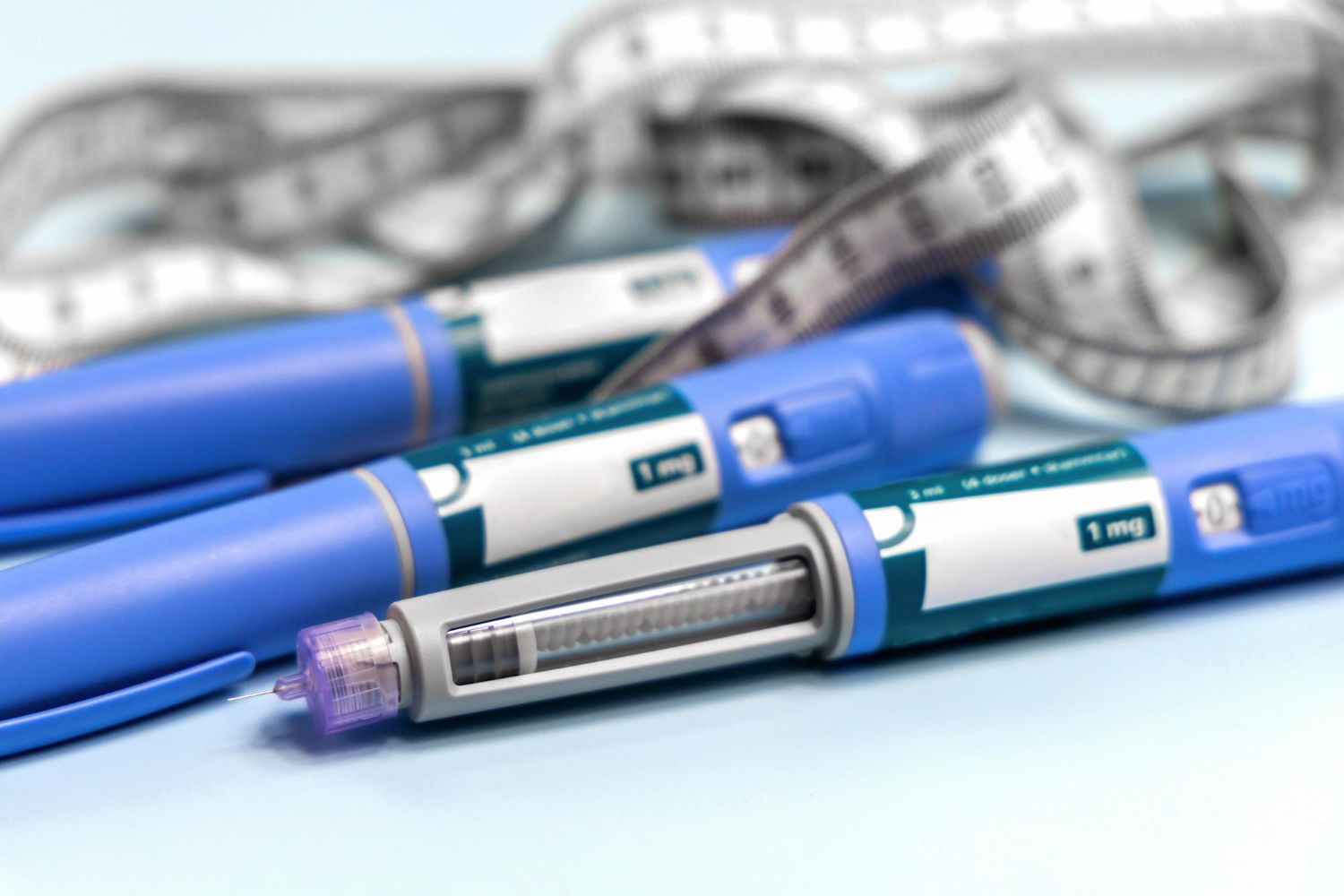 Blue insulin pens and measuring tape, suggesting diabetes management or weight control.
