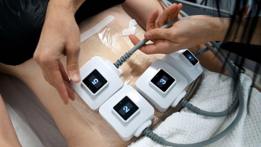 A woman is laying on a bed with a device on her stomach.