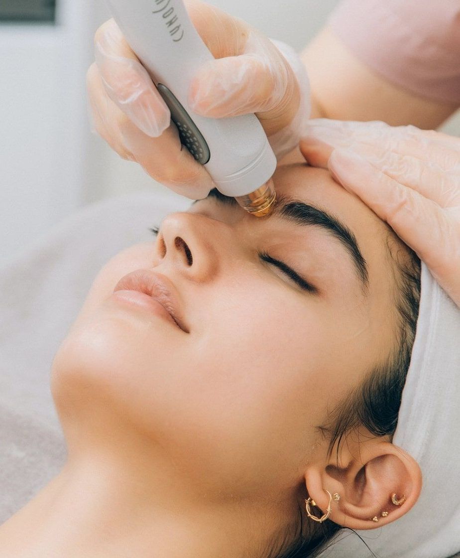 A woman is getting a tempsure envi treatment on her face.