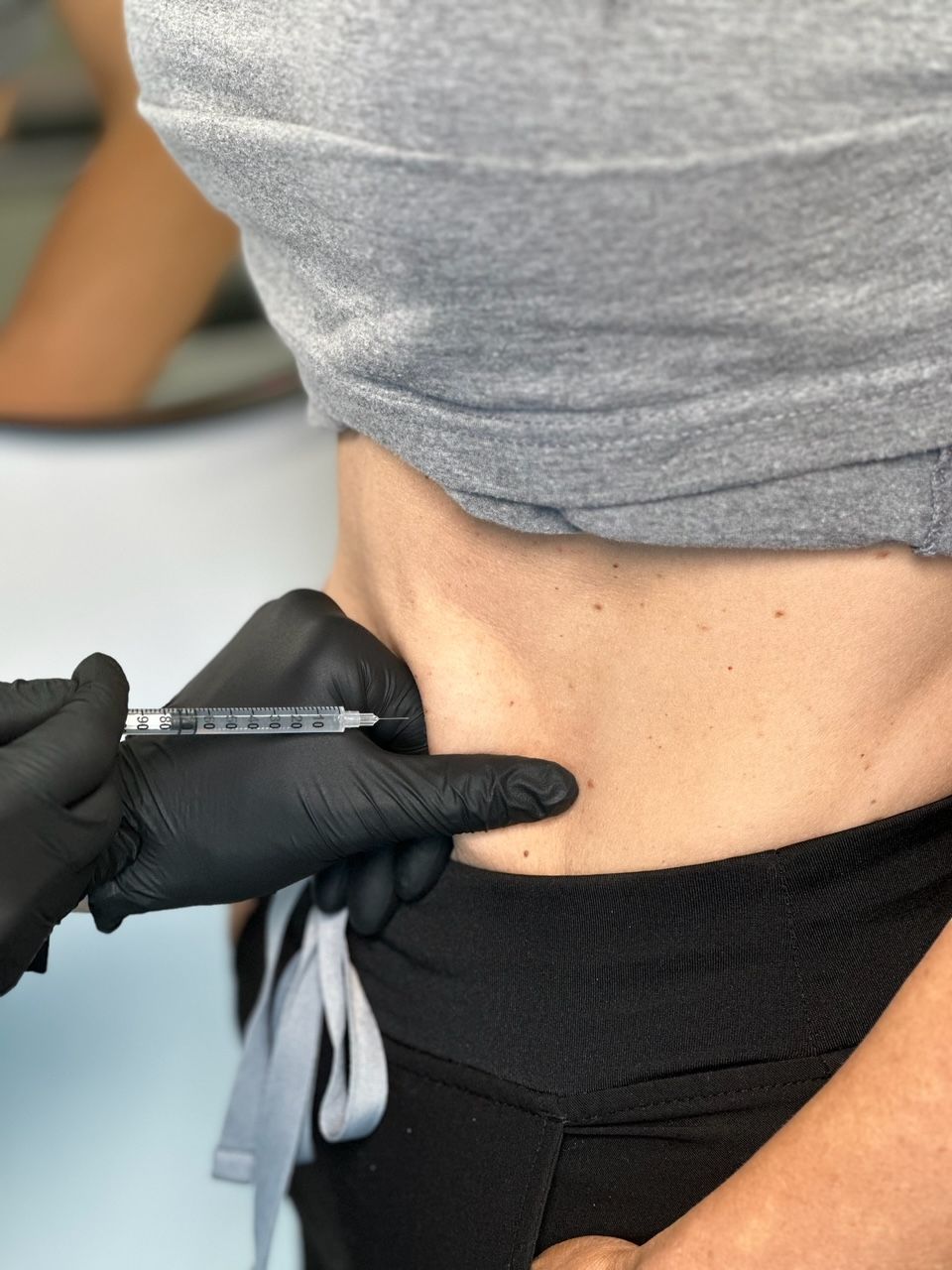 A woman is getting an injection in her stomach.