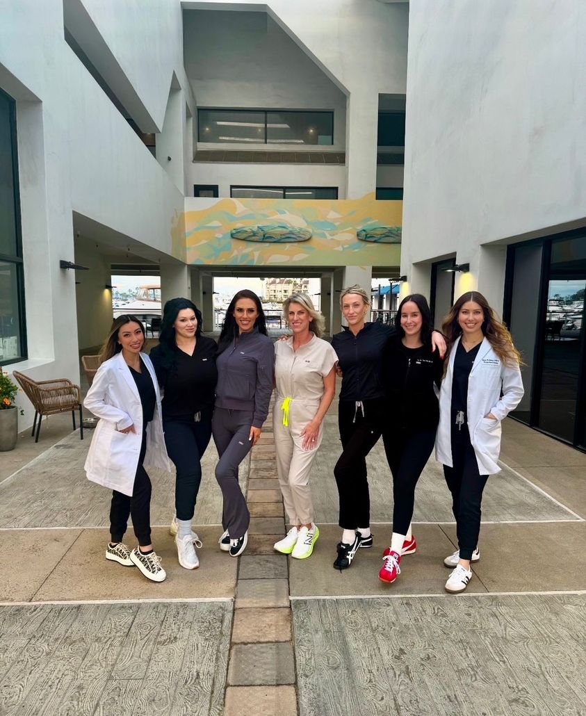 A group of women in scrubs are posing for a picture in front of a building.