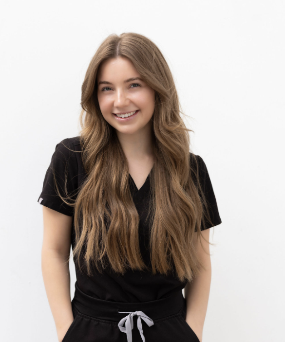 A woman in a gray scrub top and pants is smiling for the camera.