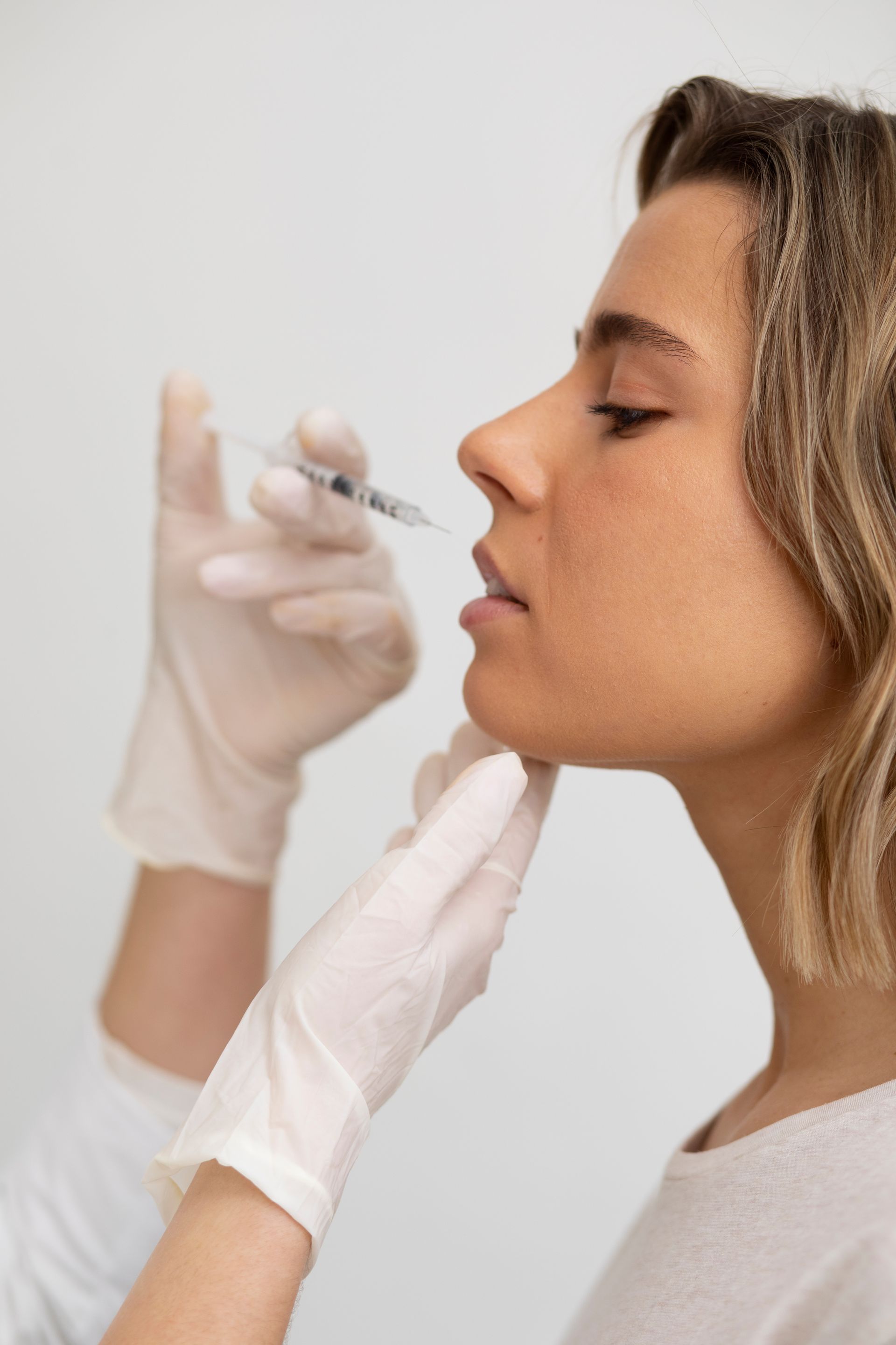 A woman is getting a botox injection in her lips.