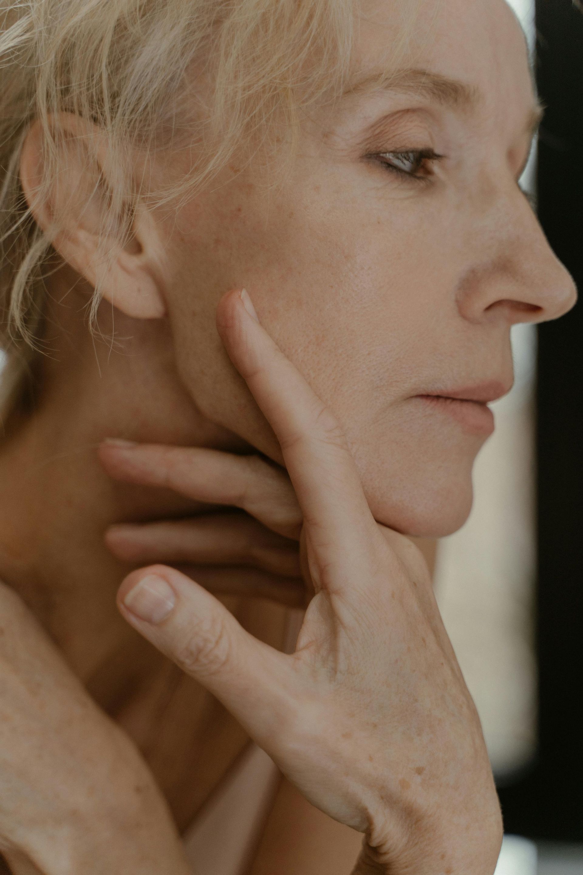 A close up of a woman 's face with her hand on her face.