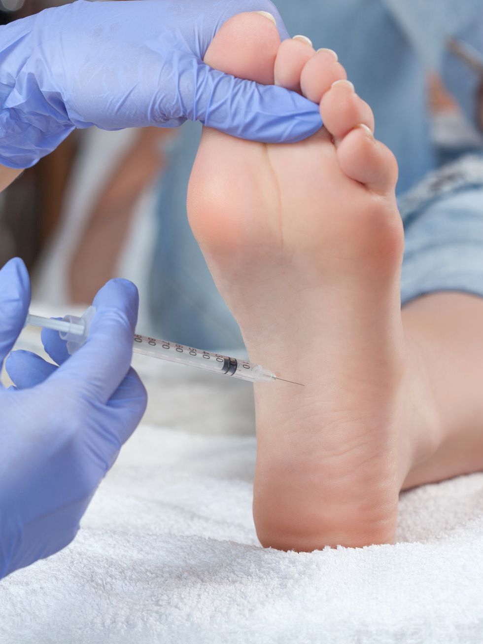 A person is getting an injection in their foot.