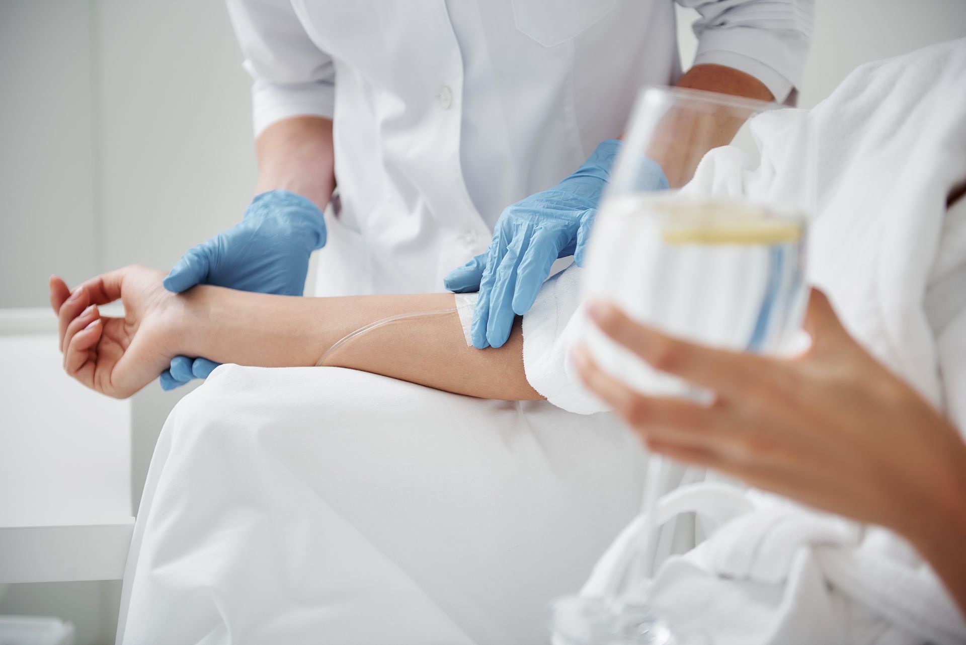 A woman is getting an injection in her arm while holding a glass of water.