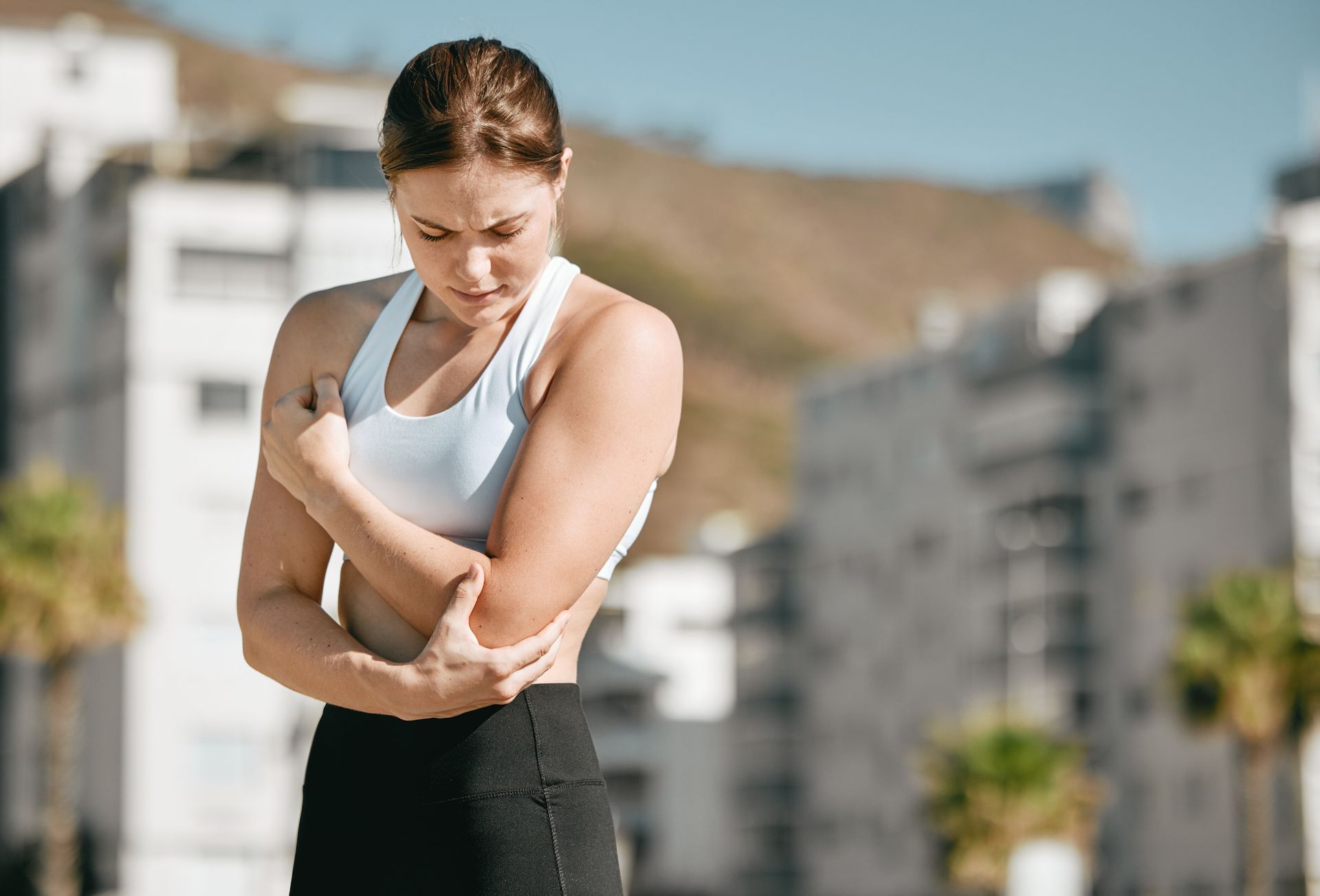 A woman is holding her elbow in pain.