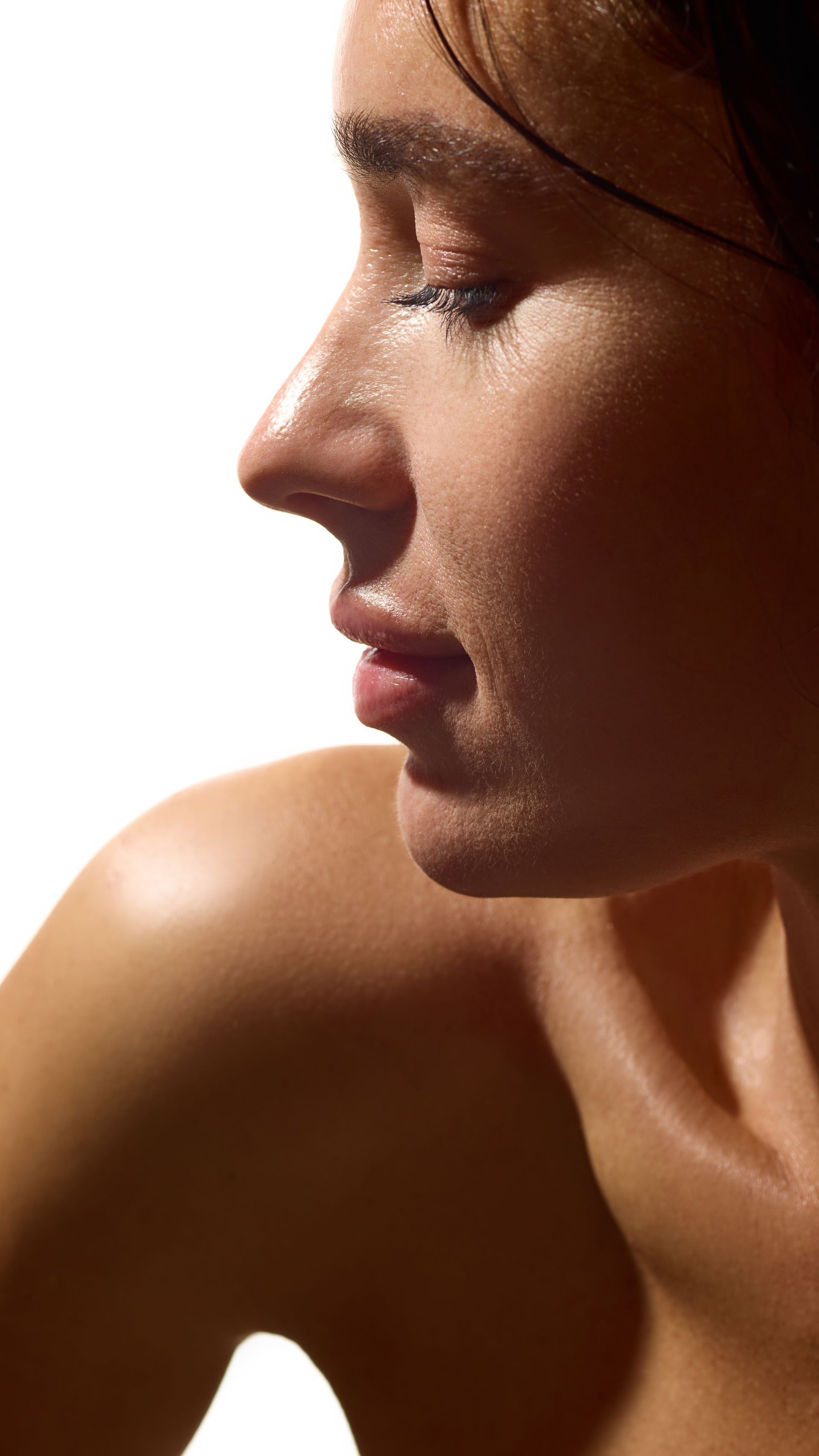 Close-up profile of a person with eyes closed, lit warmly against a dark background