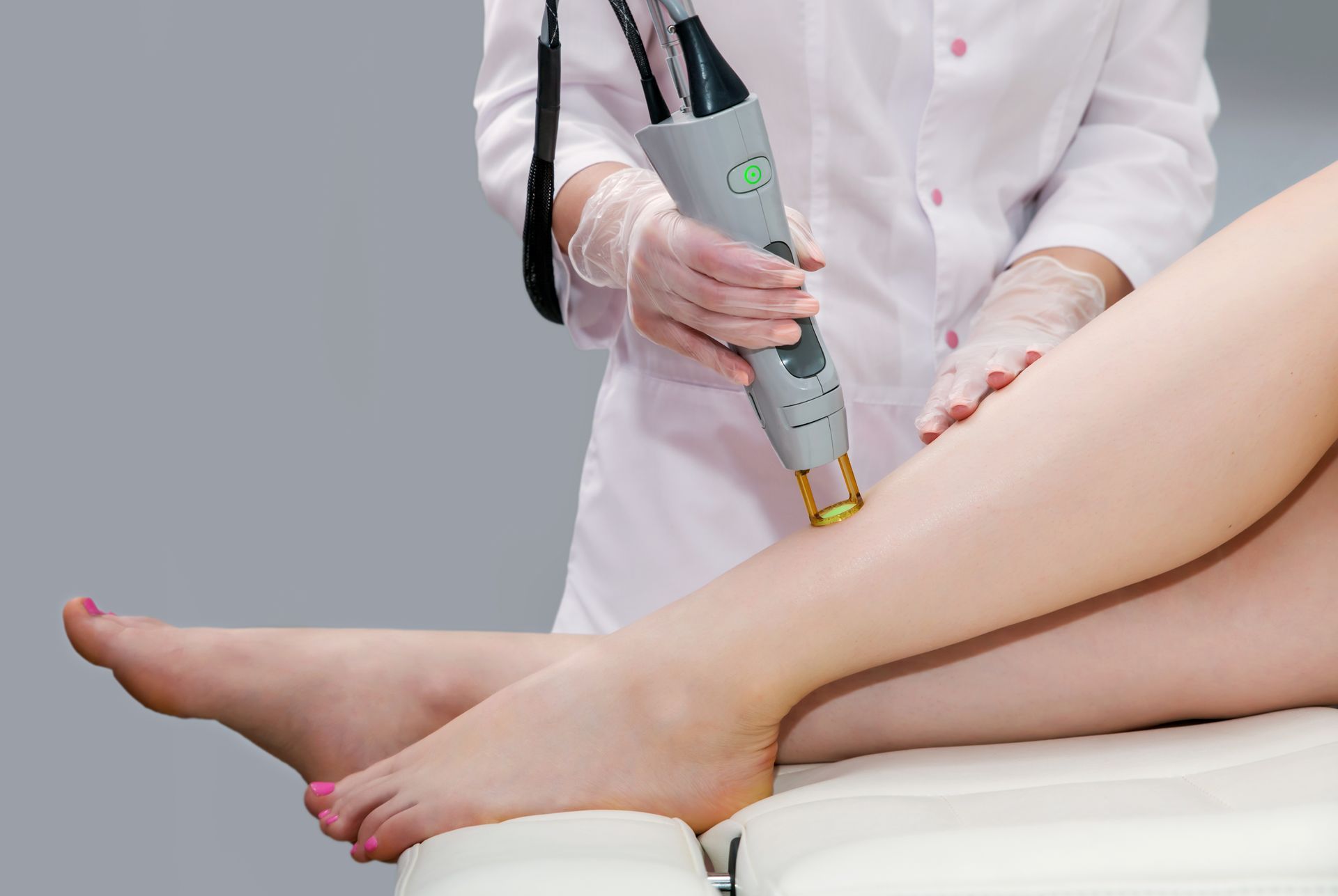 A woman is getting a laser hair removal treatment on her legs.