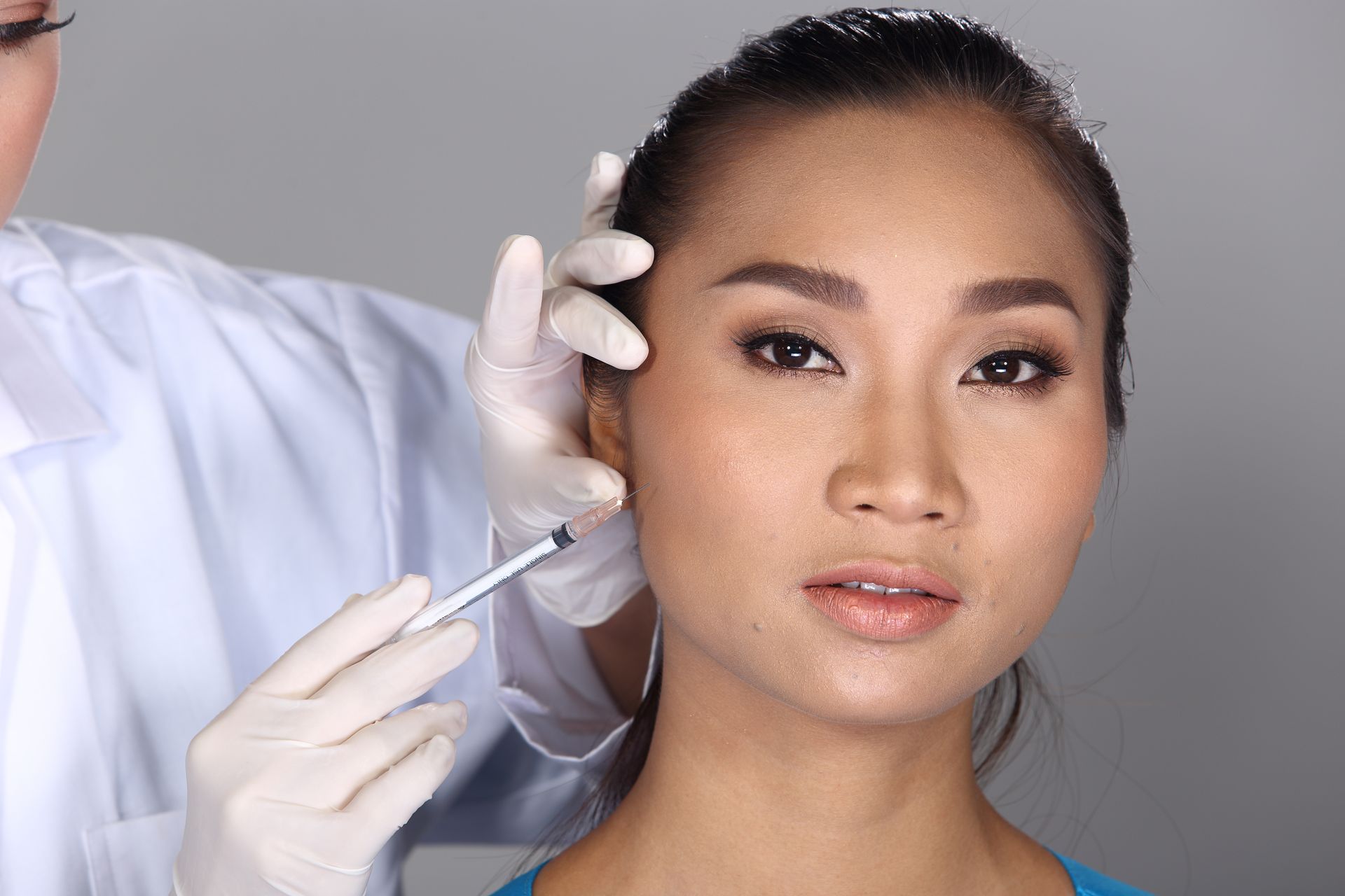 A woman is getting an injection in her face by a doctor.