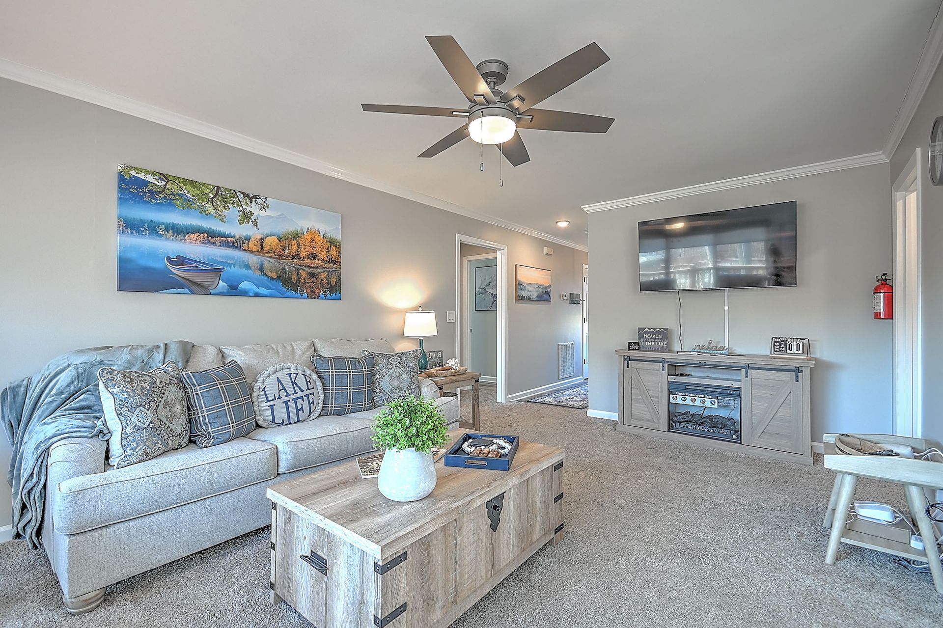 A living room with a couch , coffee table , television and ceiling fan.