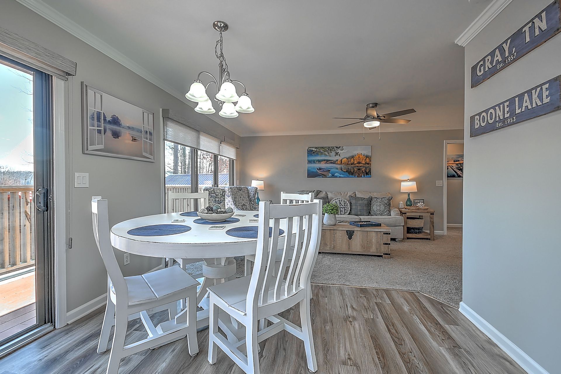 A dining room with a table and chairs and a sliding glass door leading to a living room.
