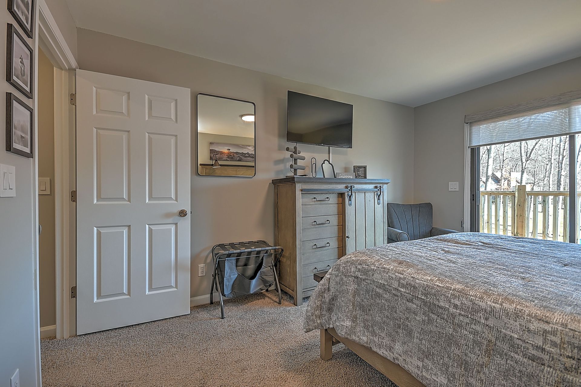 A bedroom with a bed , dresser , television and mirror.