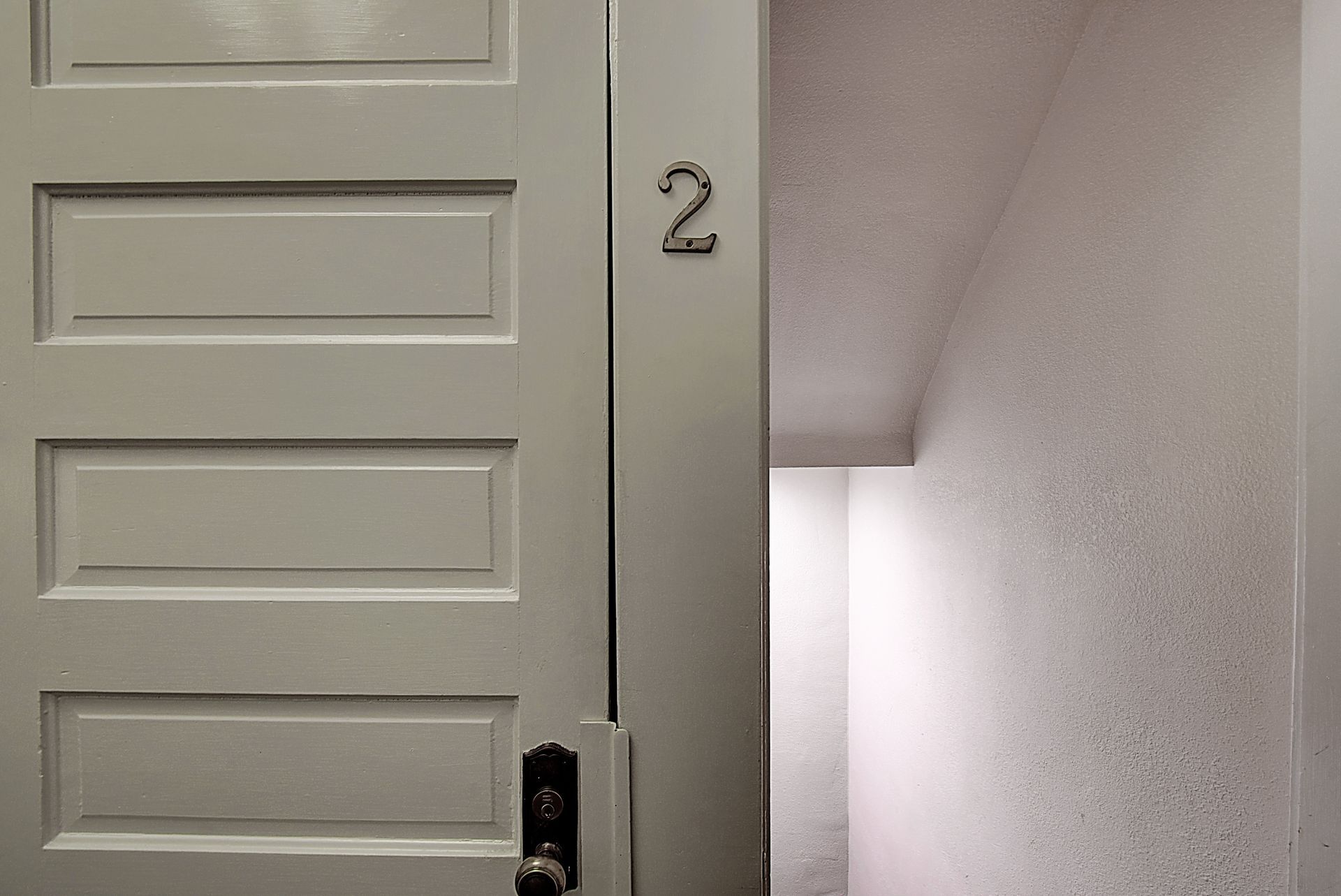 A white door with the number 2 on it is open to a room.