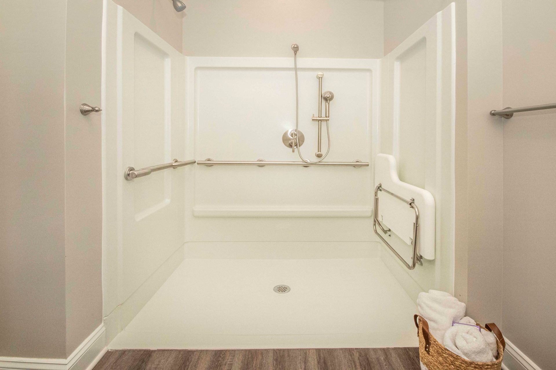 A bathroom with a walk in shower and a basket of towels.