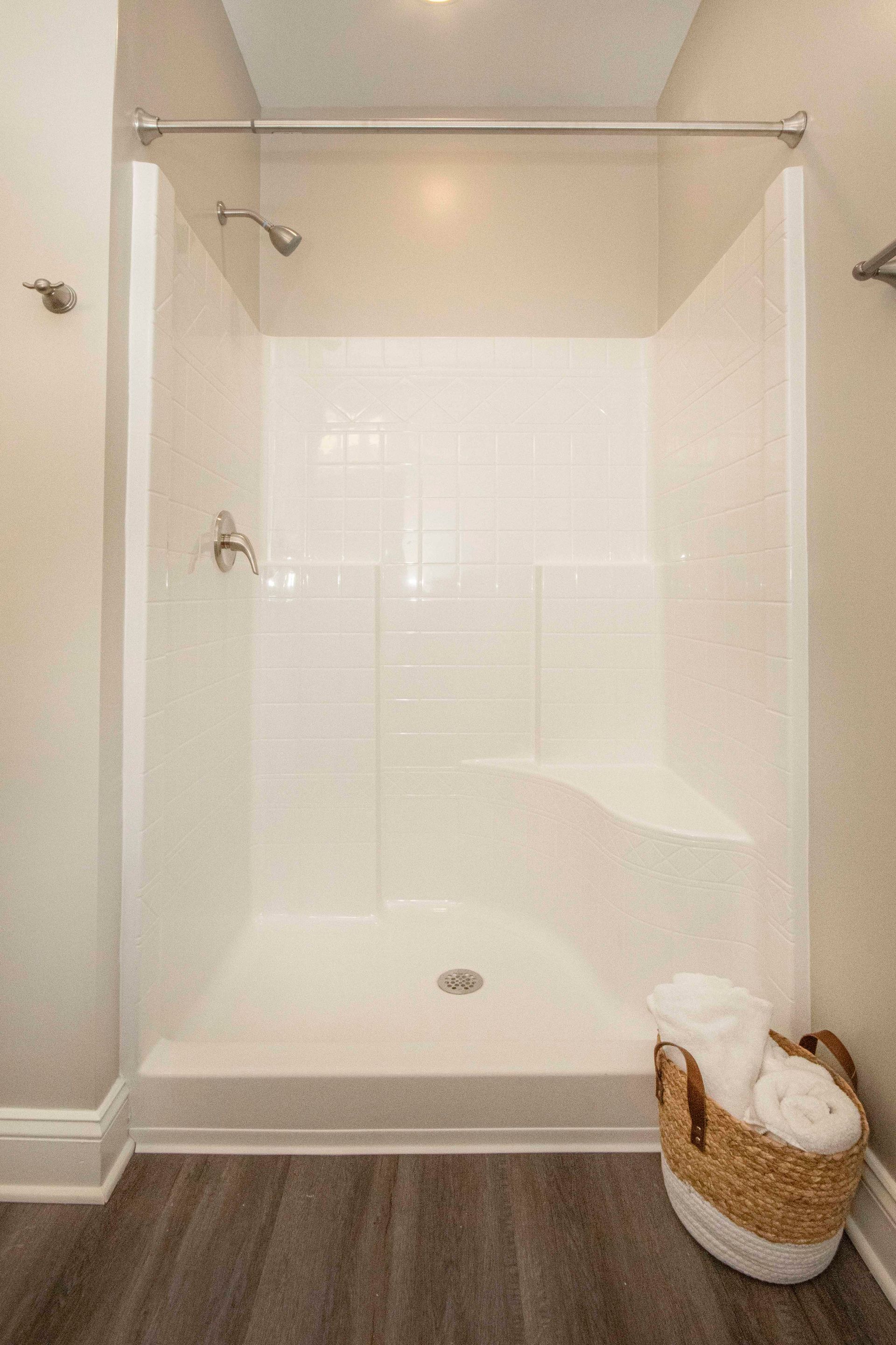 A bathroom with a walk in shower and a basket of towels.