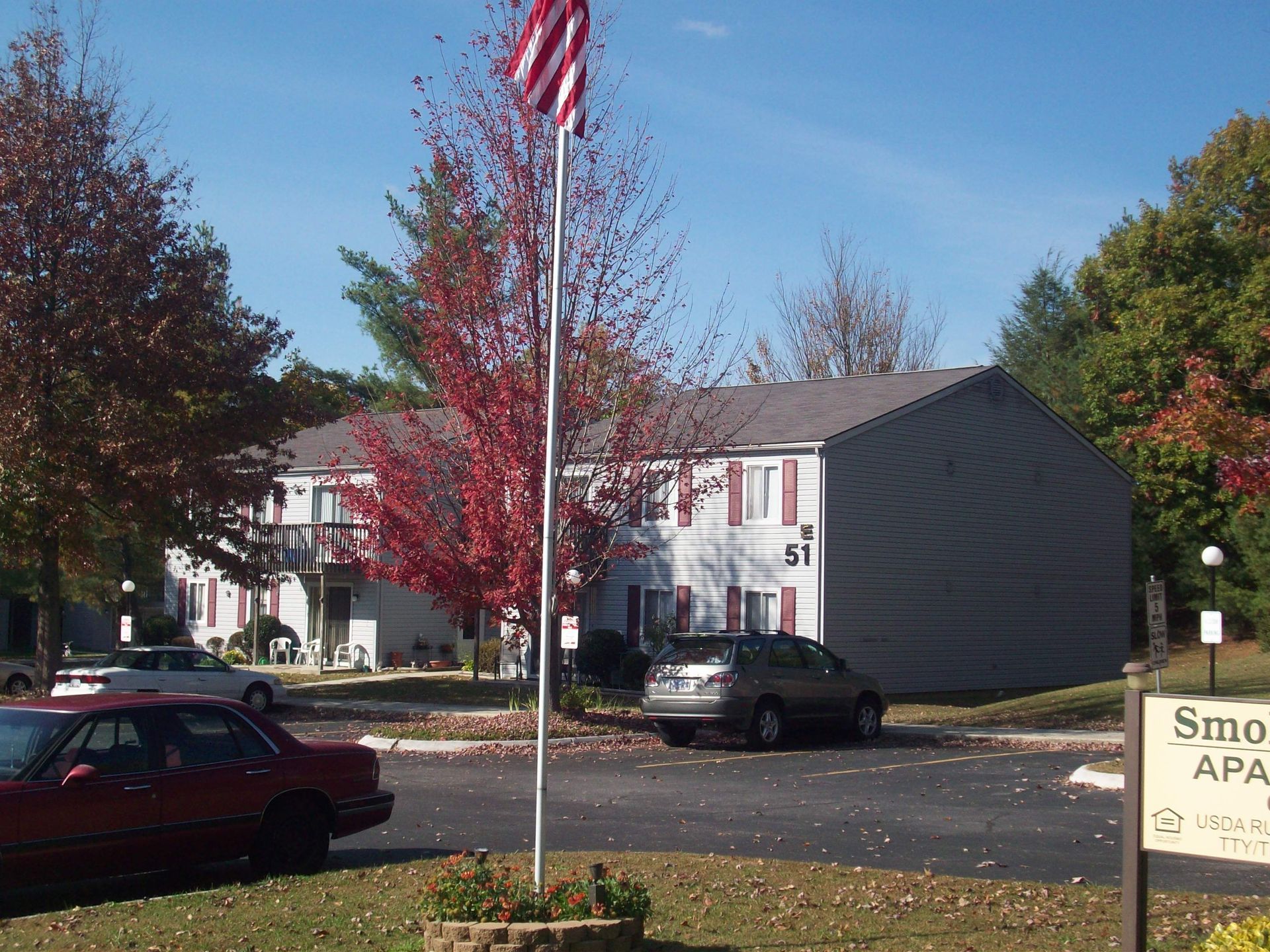 A red car is parked in front of a building with the number 51 on it