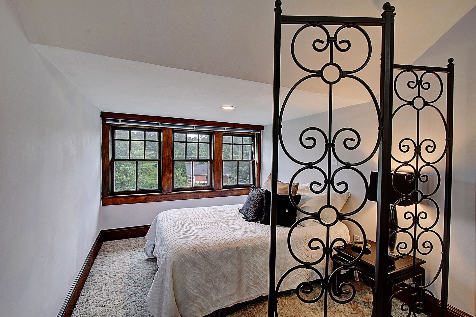 A bedroom with a bed and a wrought iron room divider