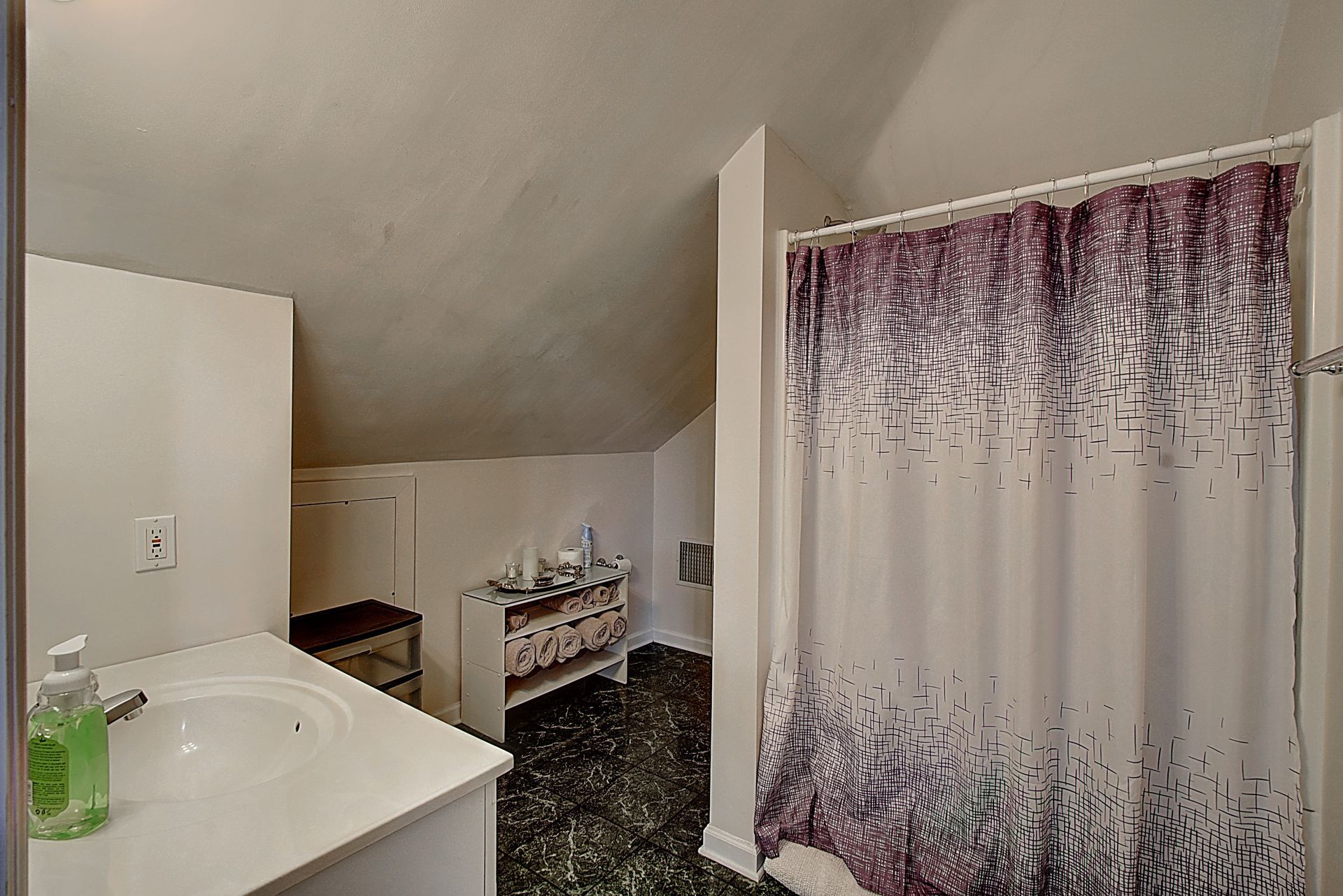 A bathroom with a shower curtain and a sink.