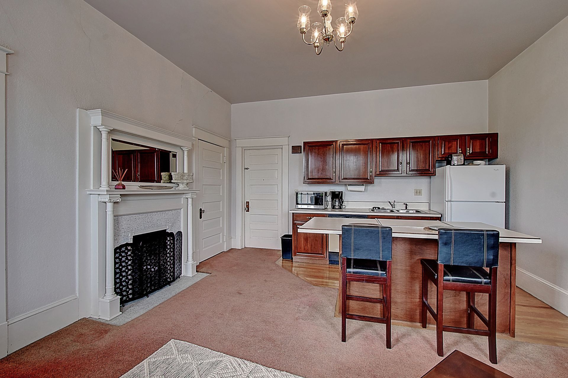 A living room with a kitchen and a fireplace