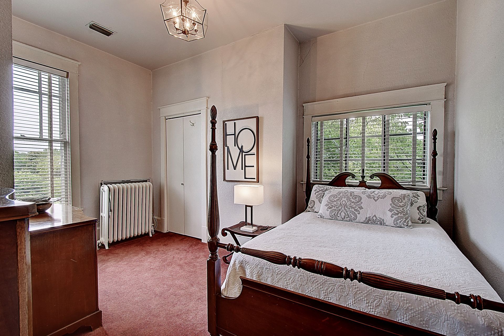 A bedroom with a four poster bed and a sign that says home