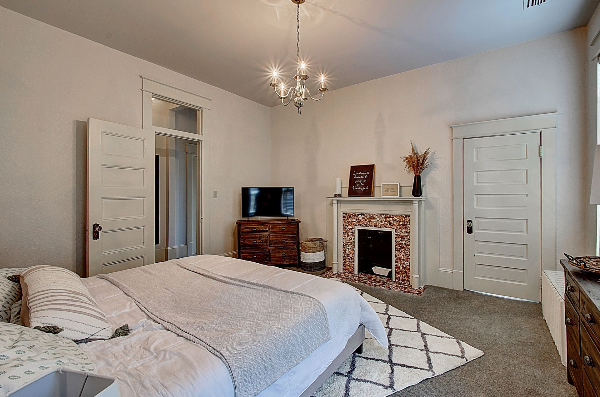 A bedroom with a large bed , fireplace and television.