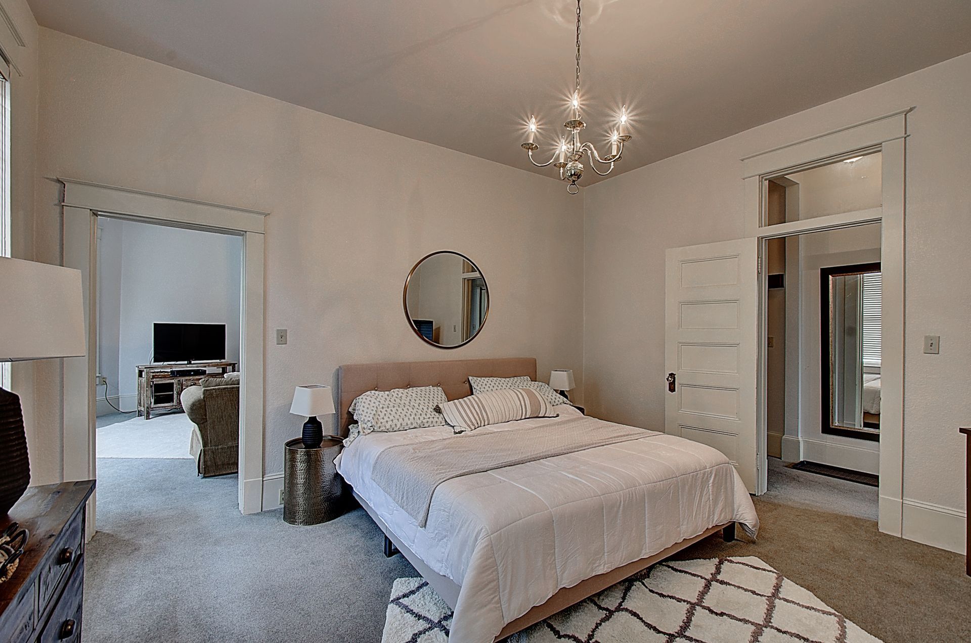 A bedroom with a large bed and a chandelier hanging from the ceiling.