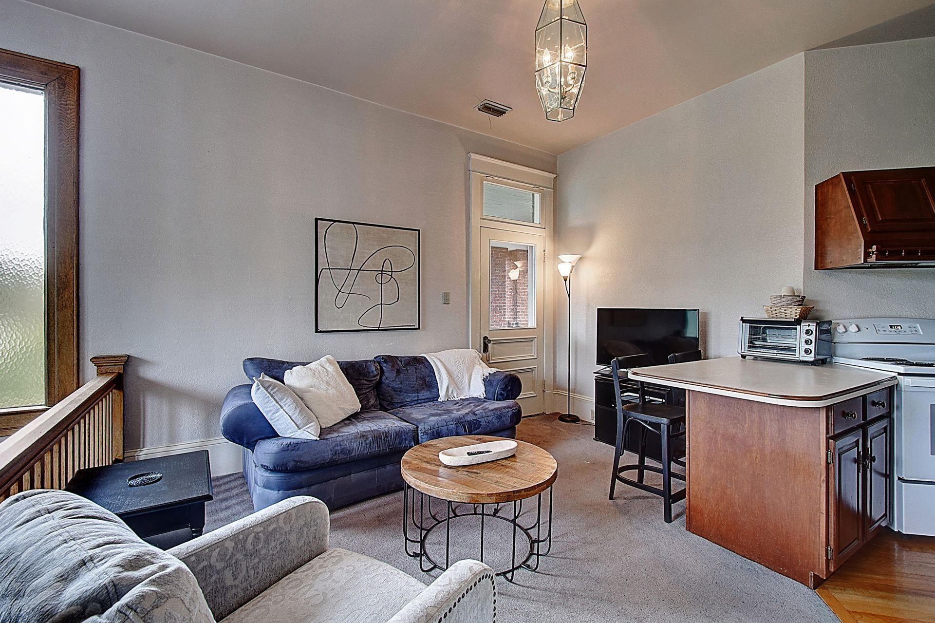 A living room with a couch , chair , table and television.