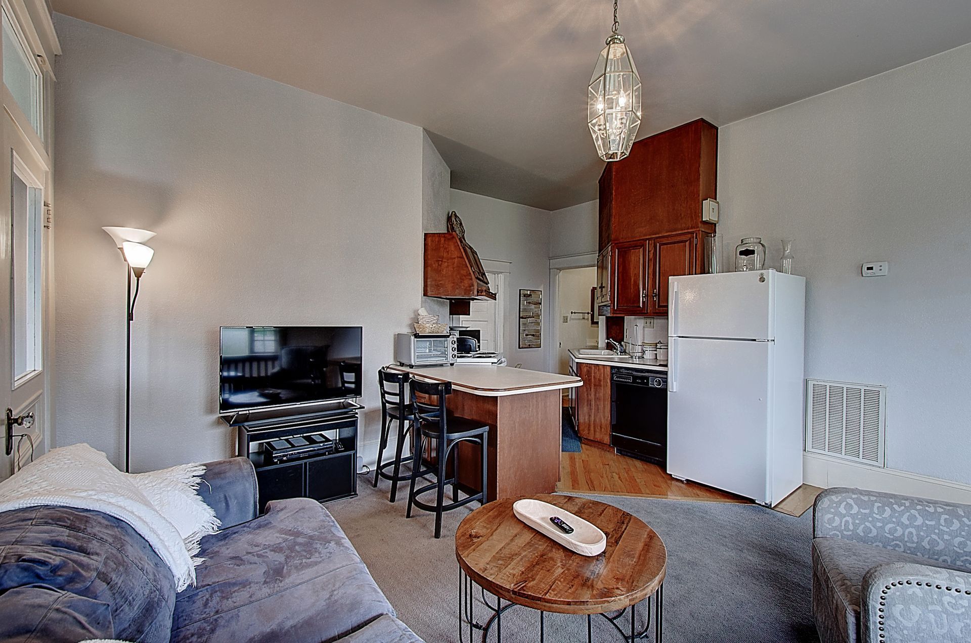 A living room with a couch a table and a refrigerator