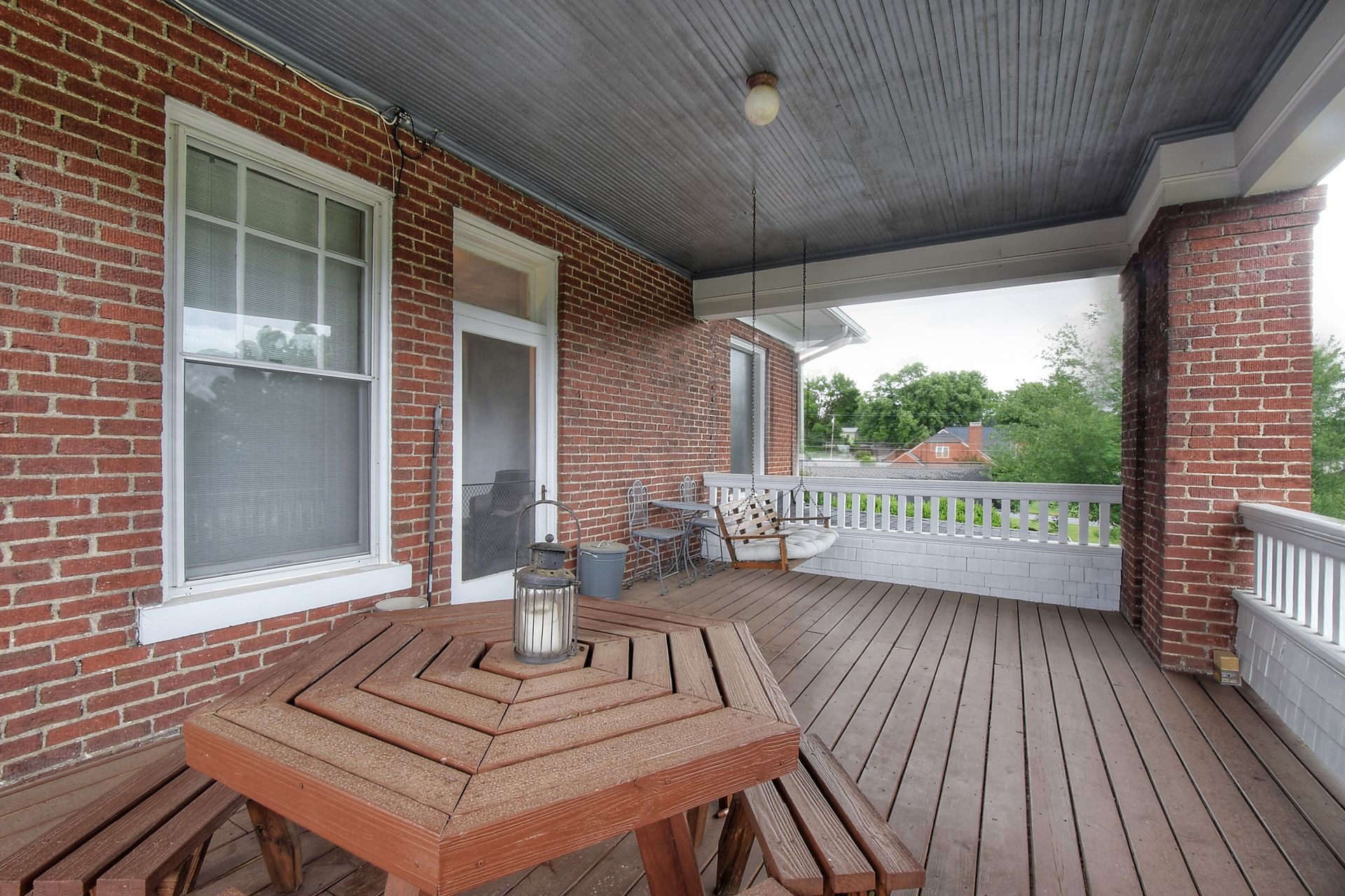 A brick house with a porch with a wooden table and benches.