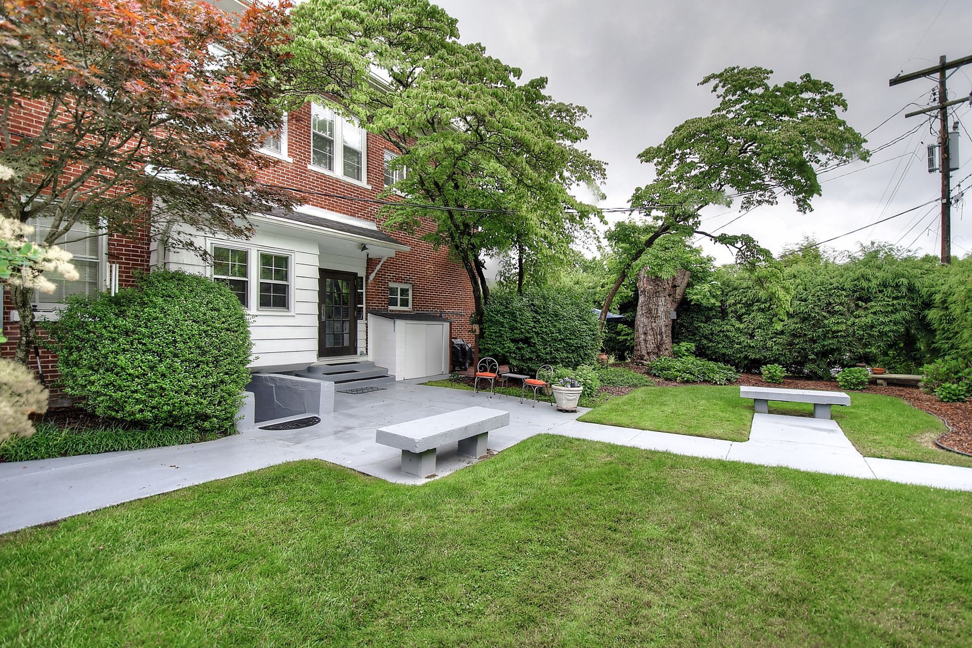 A house with a large lawn and a bench in front of it.