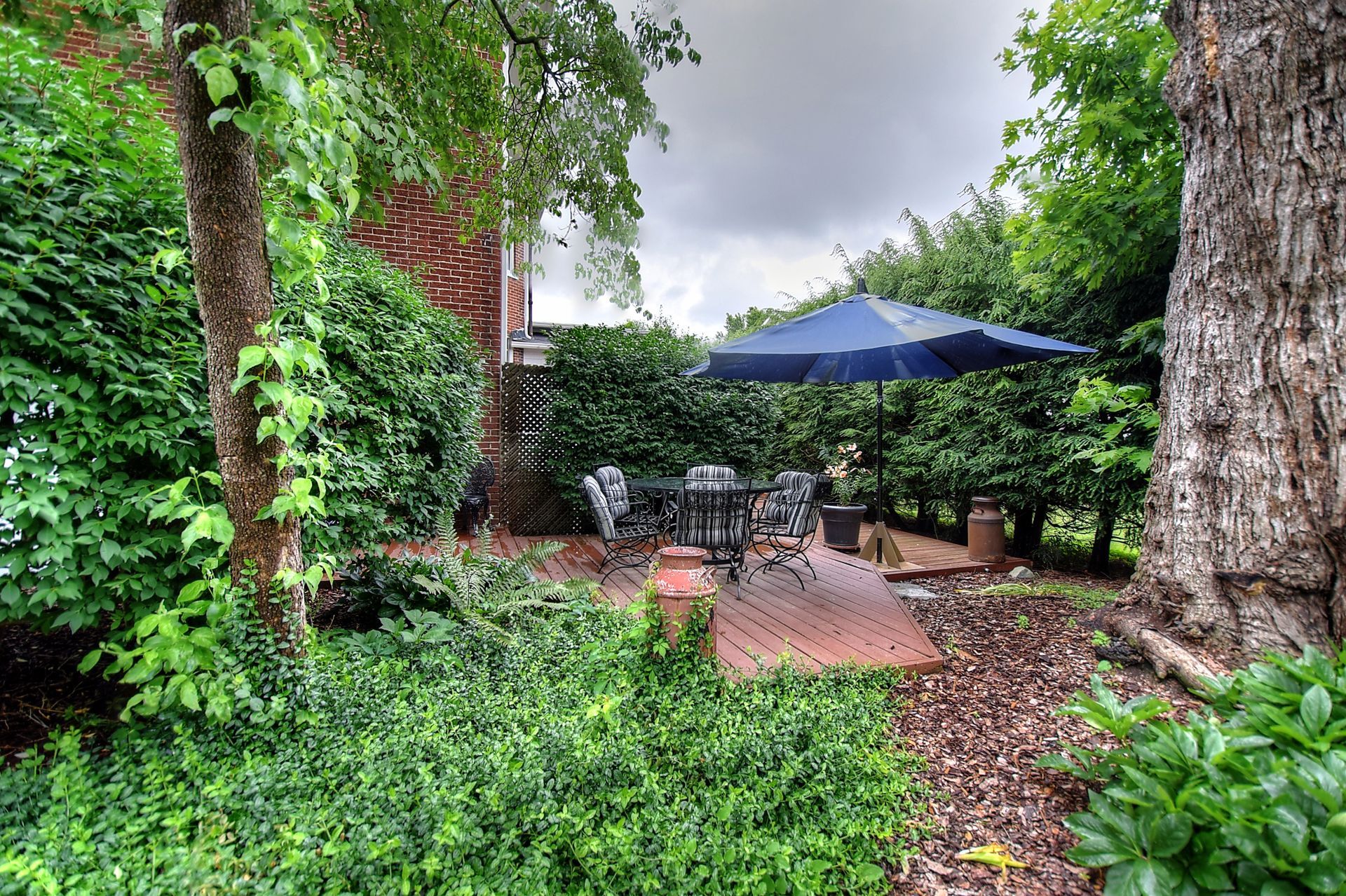 There is a patio with a table and chairs and an umbrella in the backyard.