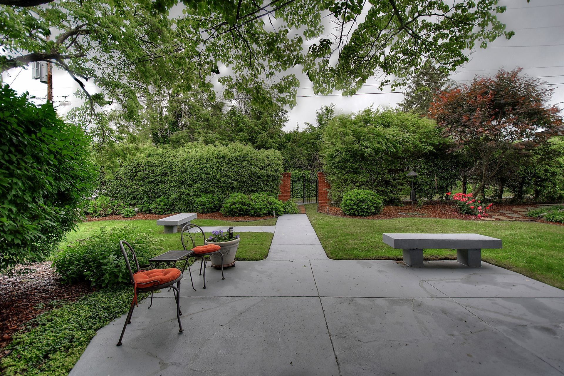 A patio with chairs and a bench in a garden