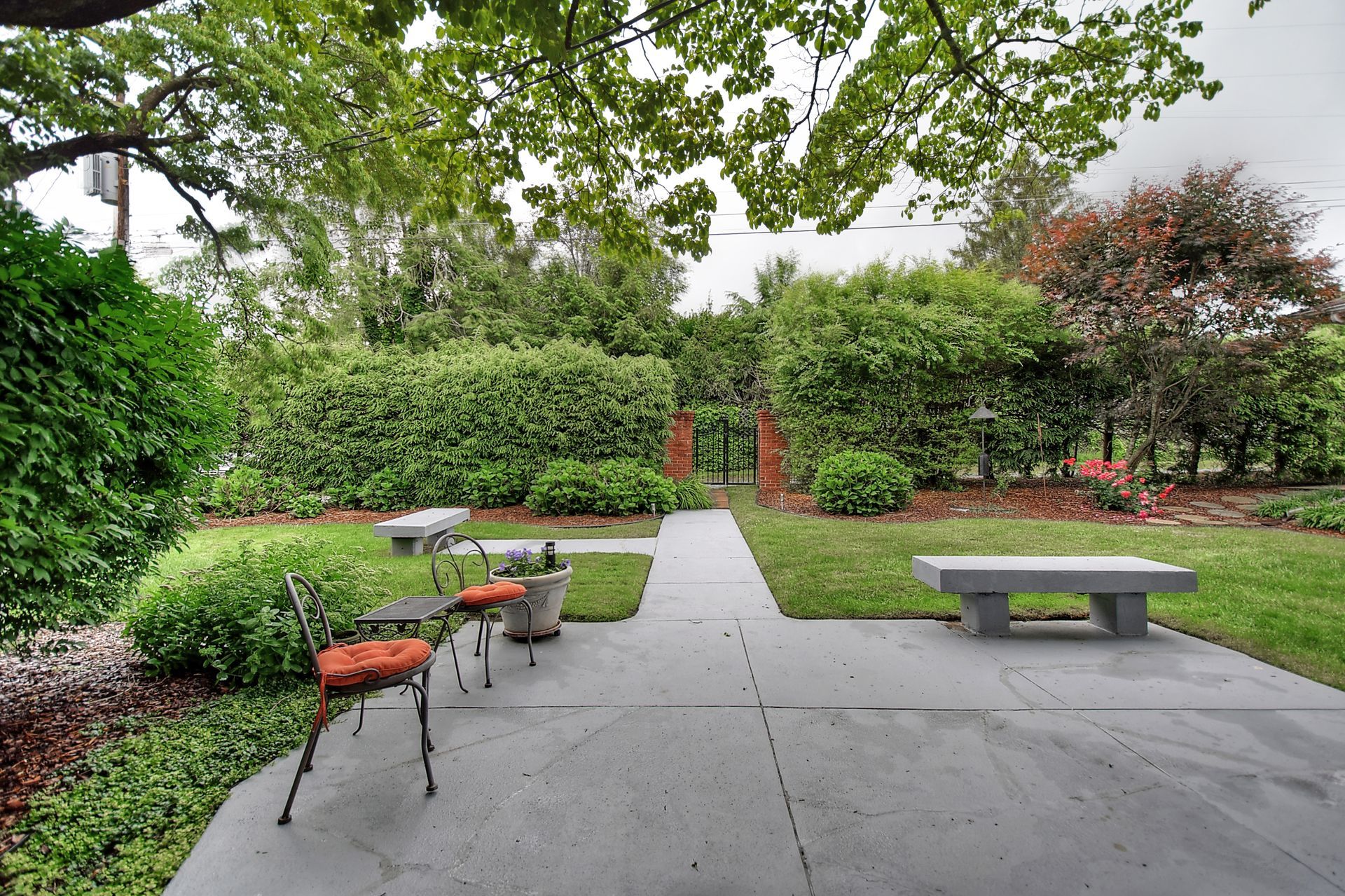 A patio with chairs and a bench in a garden