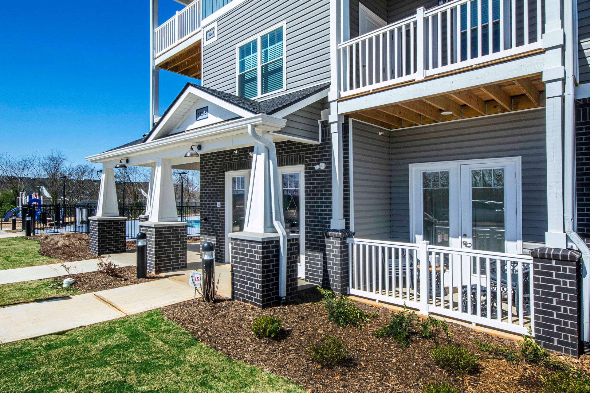A large apartment building with a porch and a playground in the background.