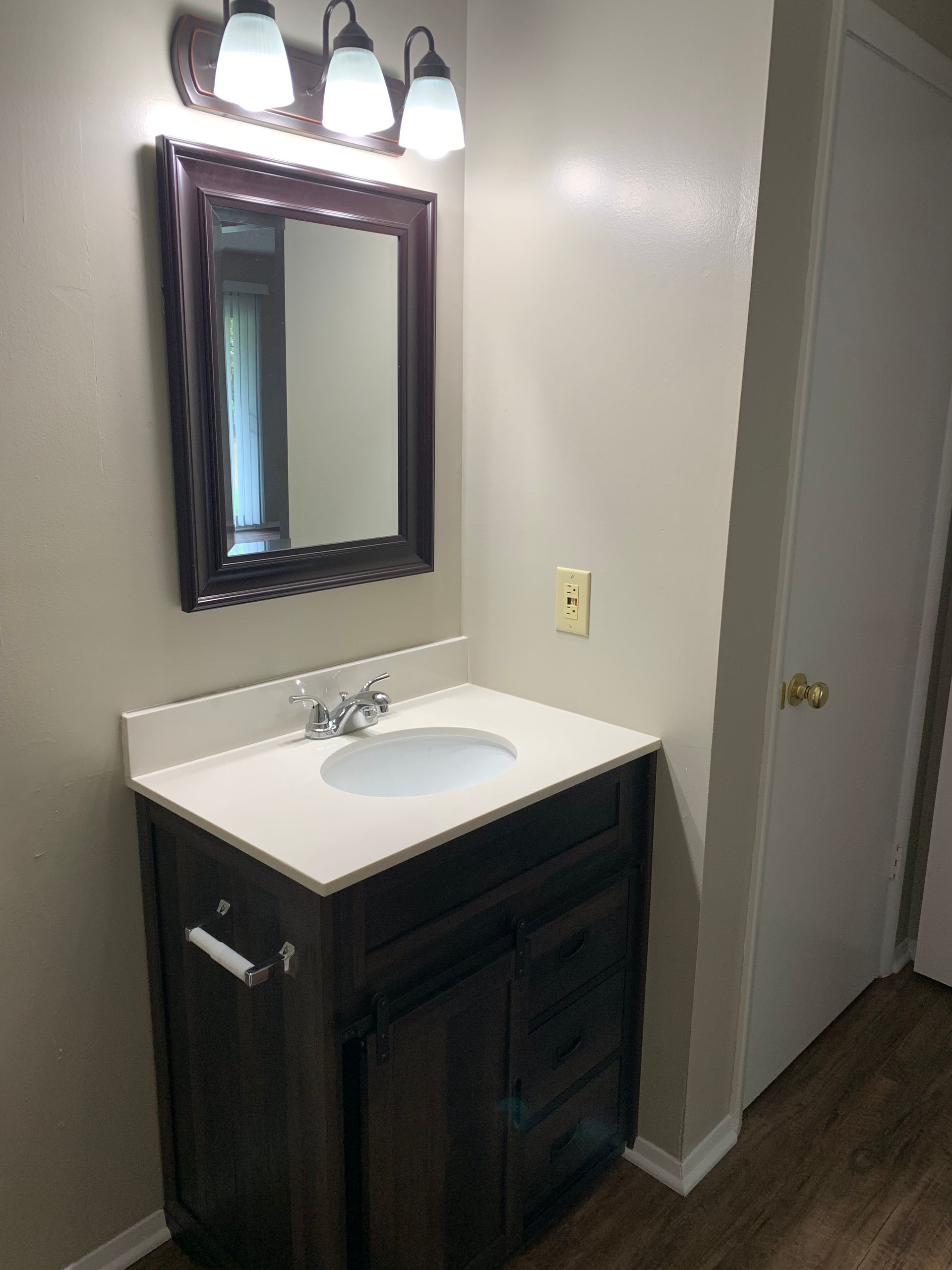 A bathroom with a sink , mirror and light fixtures.