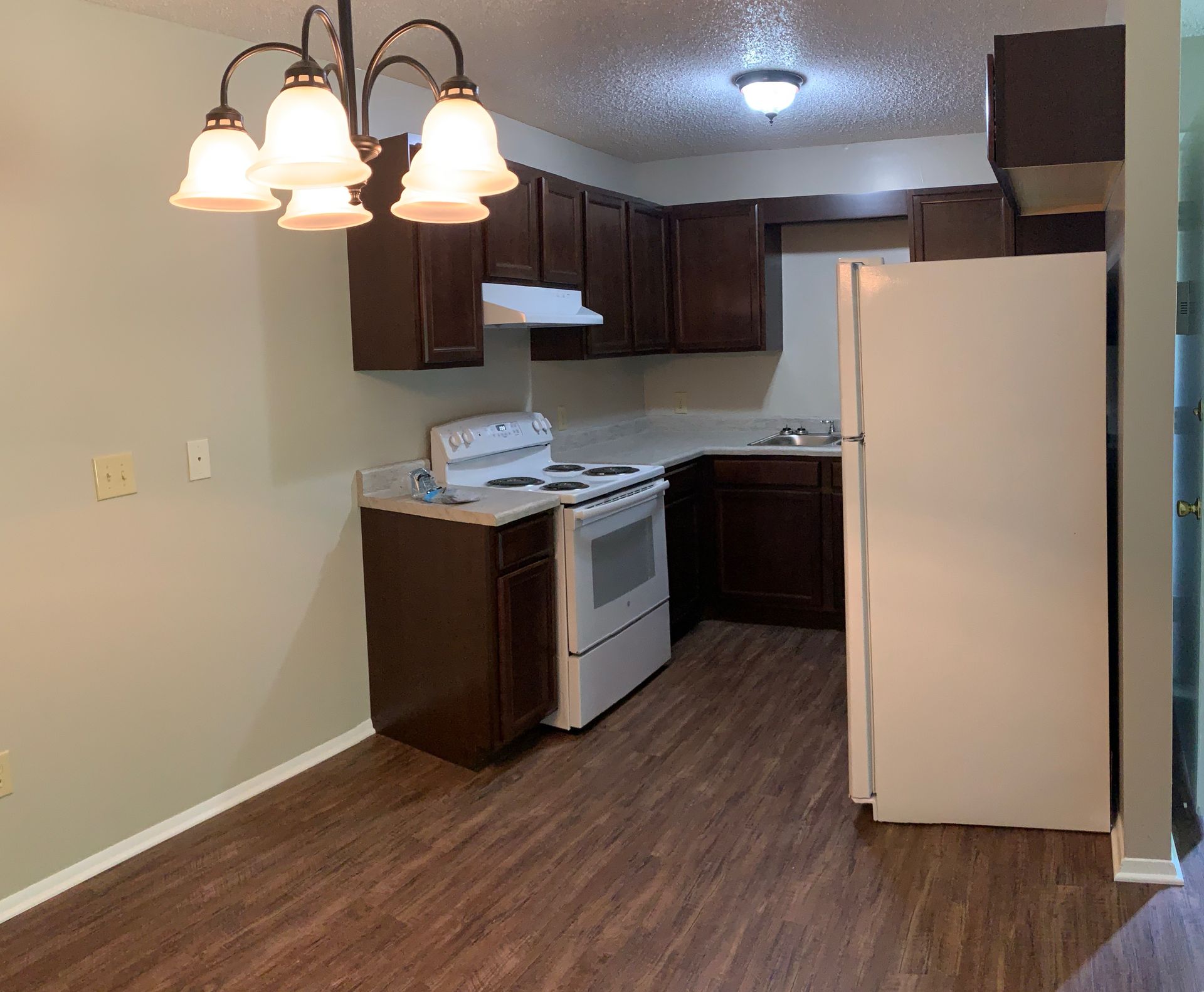 A kitchen with a stove , refrigerator , sink and cabinets.