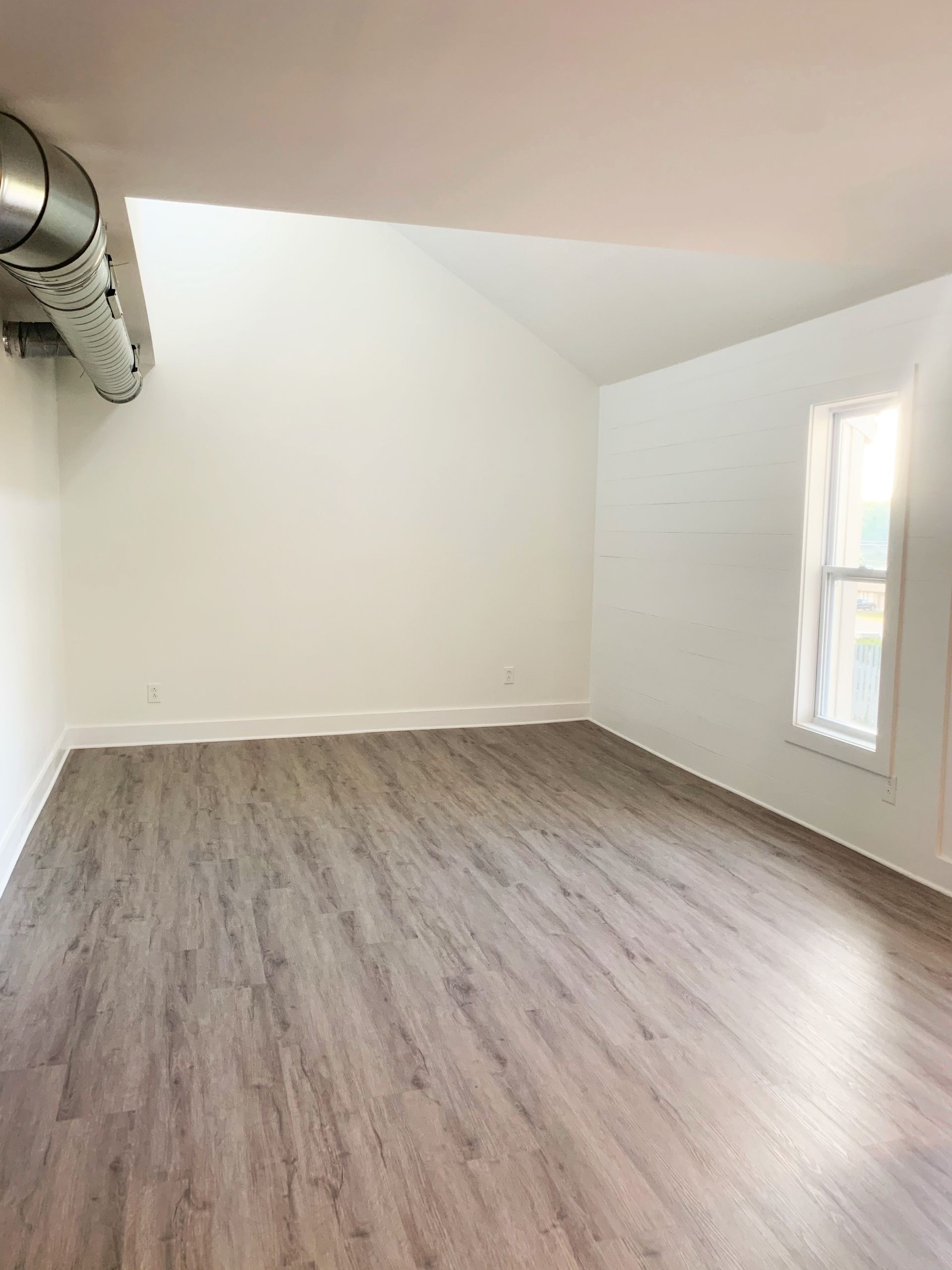 An empty room with hardwood floors and white walls.