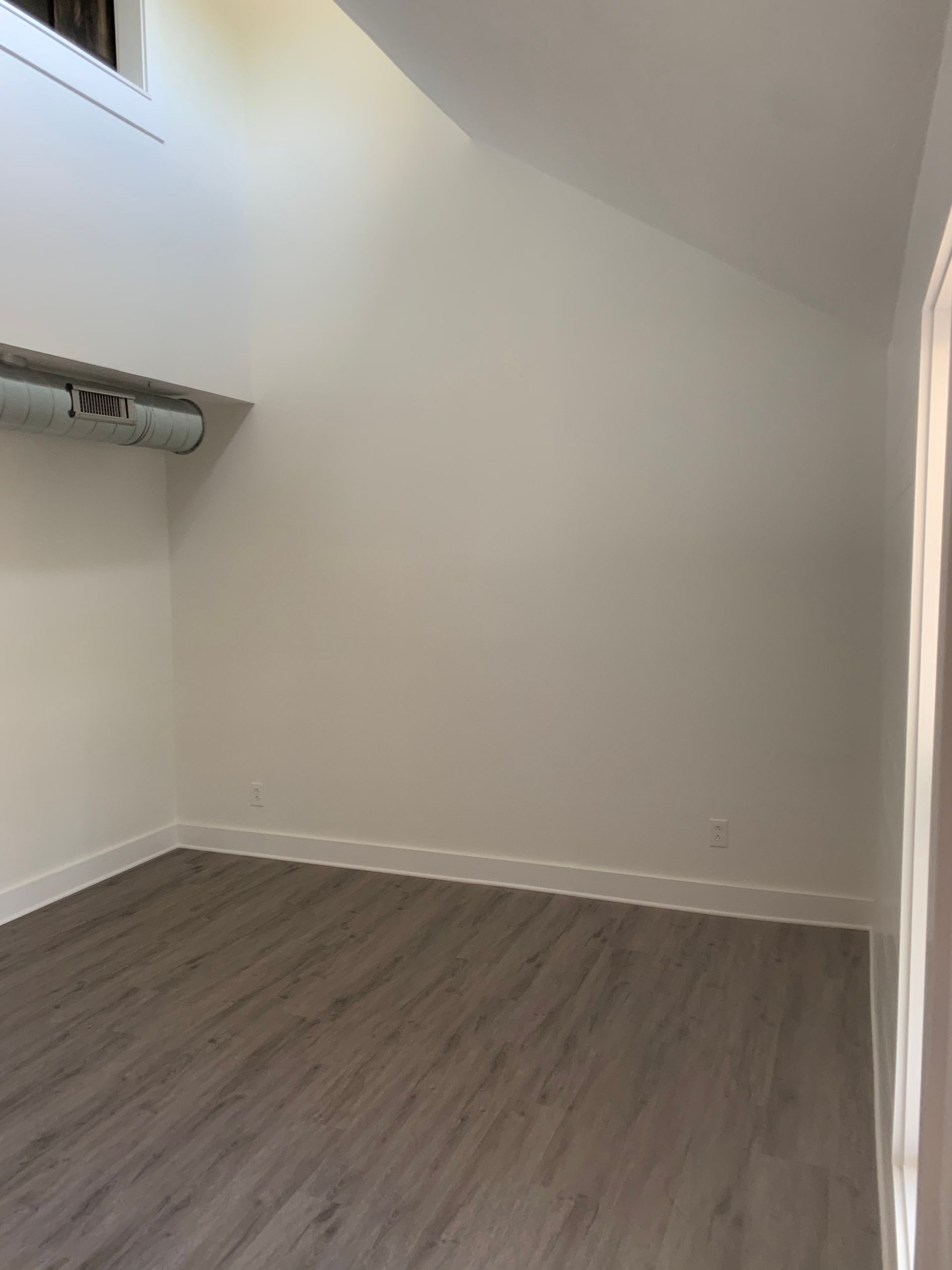 An empty room with hardwood floors and white walls.