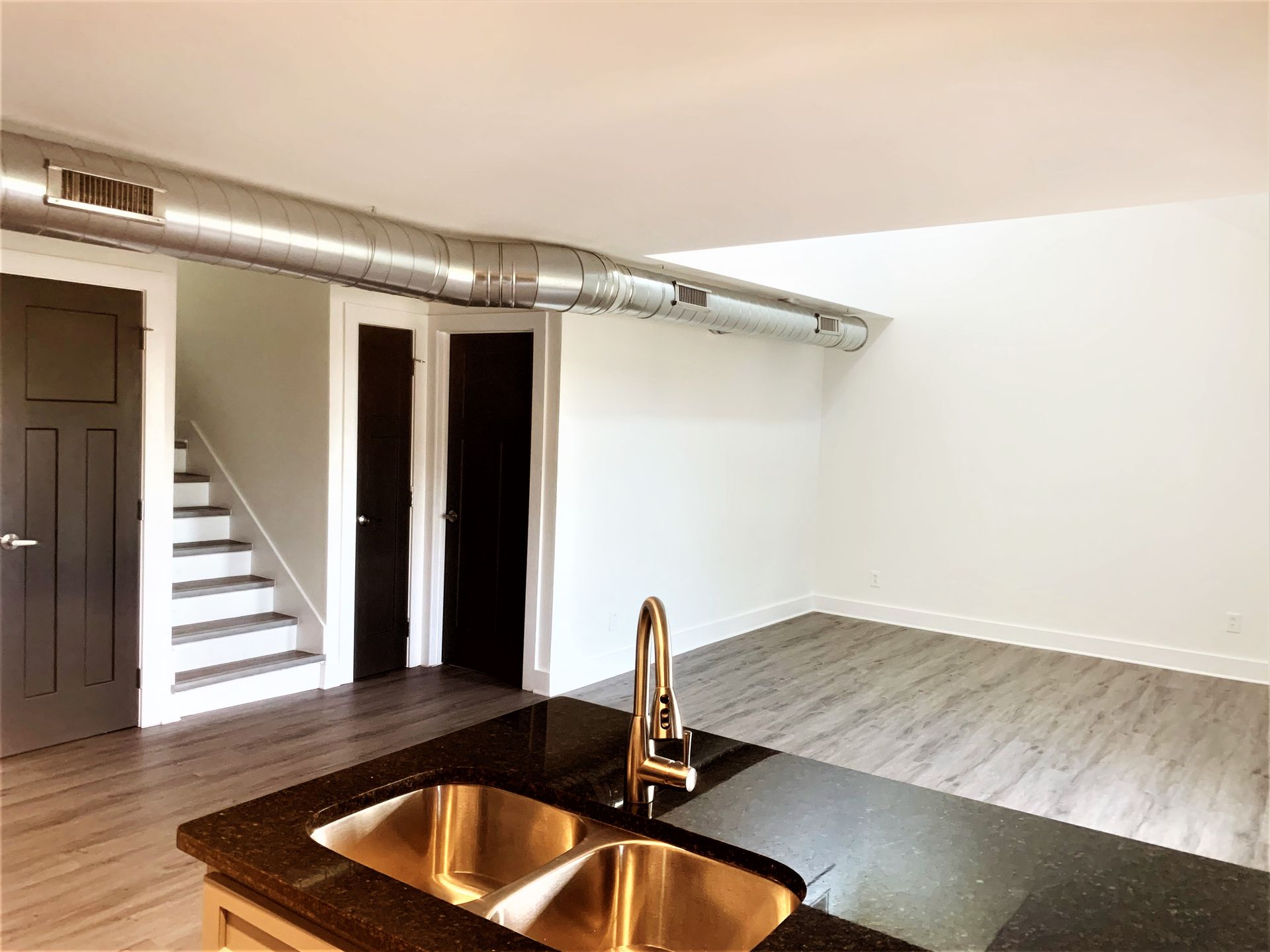 A kitchen with a sink and stairs in the background