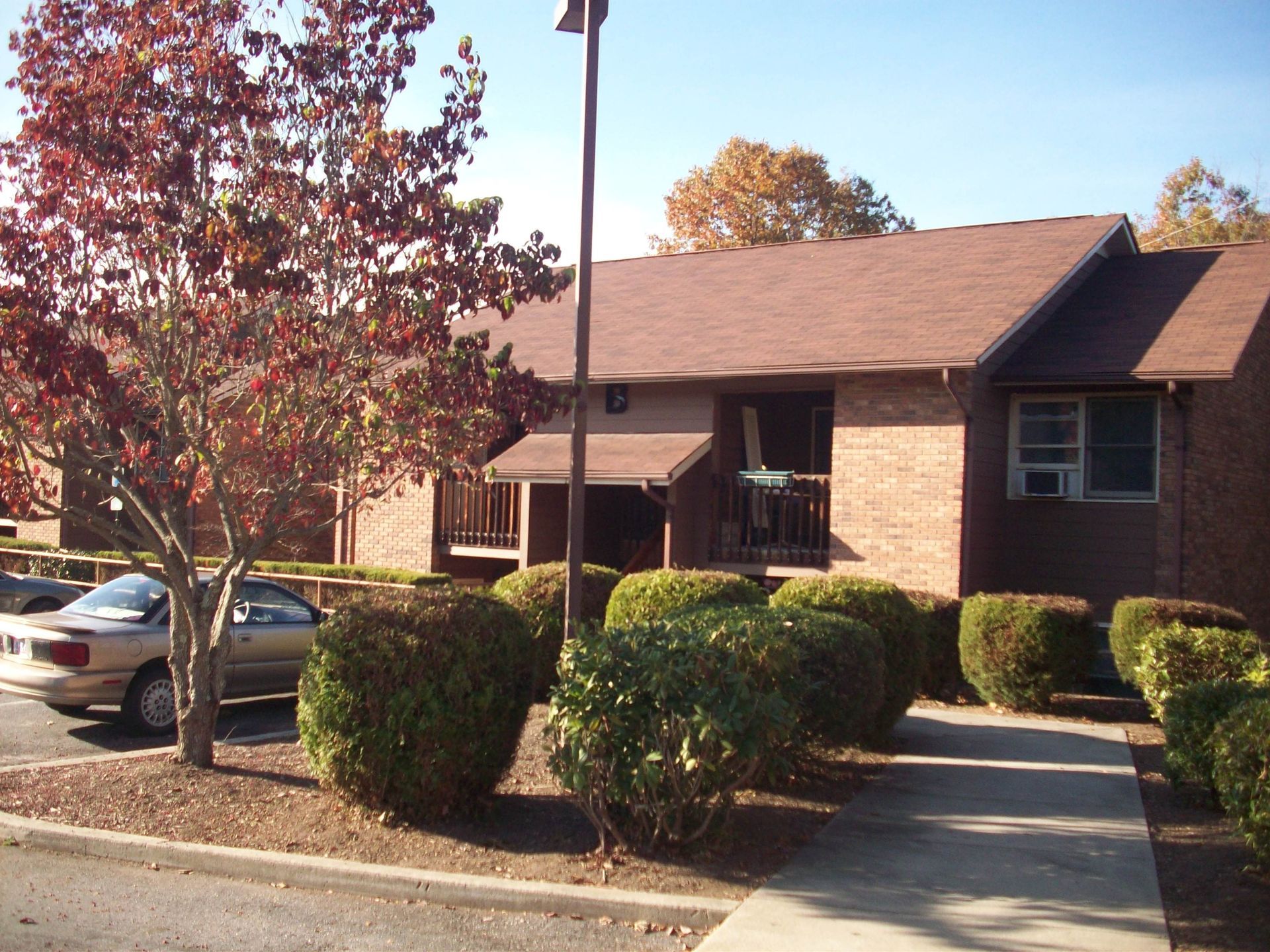 A white car is parked in front of a brick house