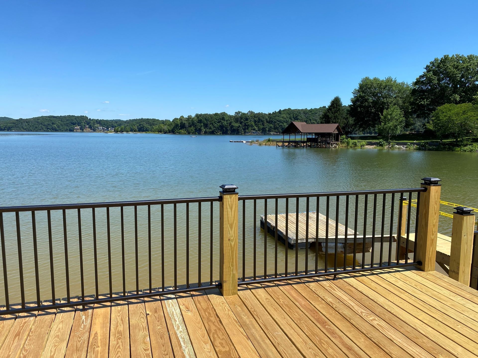 A wooden deck overlooking a lake with a metal railing